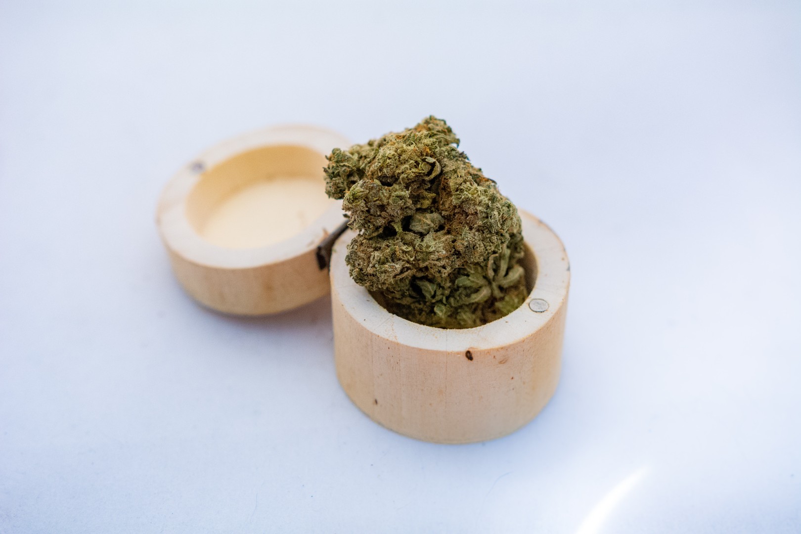 Eine Cannabisblüte in einer geöffneten Dose aus Bambus