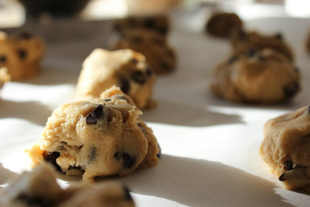 Ein Backblech mit mehreren runden Cookie-Teig-Kugeln.