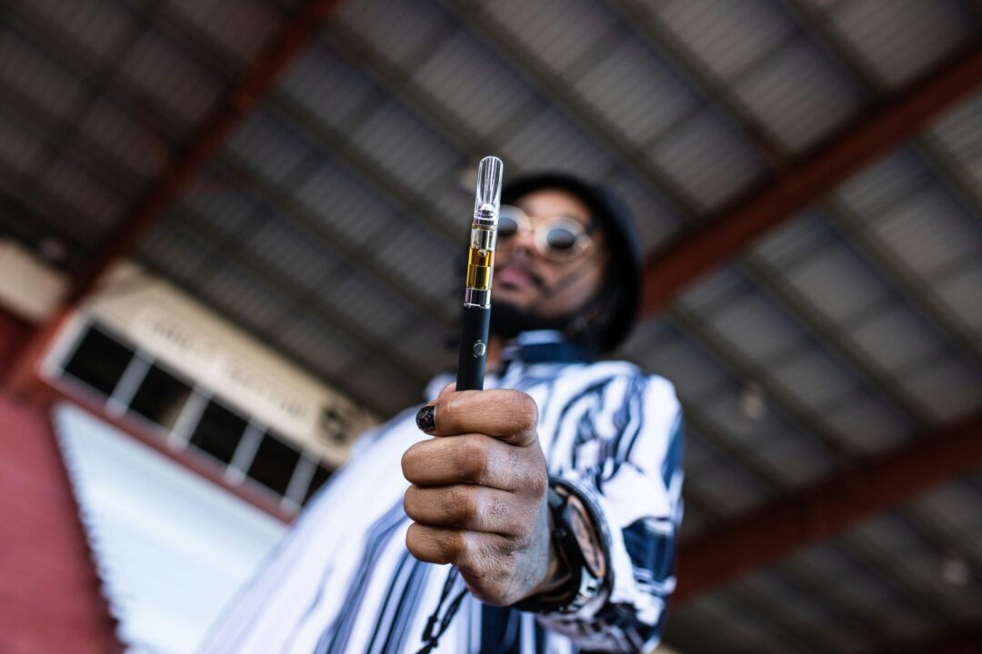 Ein Mann hält eine Vape Kartusche mit THC-Extrakt in die Kamera